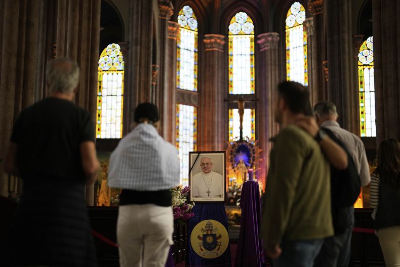 La gente se detiene frente a una fotografía del papa Francisco en la iglesia católica de San Antonio en Estambul, Turquía, el lunes 21 de abril de 2025. (AP Foto/Khalil Hamra)