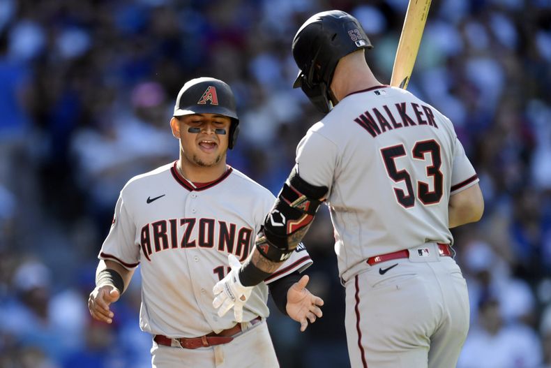 El venezolano Gabriel Moreno, de los Diamondbacks de Arizona, festeja con Christian Walker tras anotar en un wild pitch durante el juego del sábado 9 de septiembre de 2023, ante los Cachorros de Chicago (AP Foto/Paul Beaty)