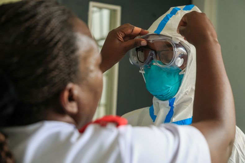 Una trabajadora de salud ayuda a un colega a ponerse el equipo de protección individual en una habitación de una unidad de aislamiento para pacientes con ébola, el miércoles 7 de octubre de 2026, en The Nairobi Hospital, Kenia. (AP Foto/Andrew Kasuku)
