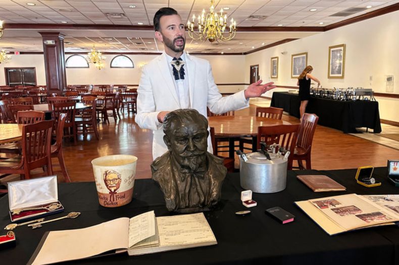 El subastador Jonathan Klunk muestra una serie de objetos personales de Harland Sanders, fundador de KFC, el miércoles 22 de julio de 2026, en Shelbyville, Kentucky. (AP Foto/Dylan Lovan)