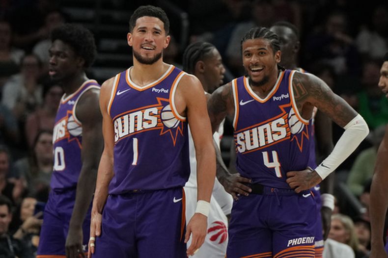 Devin Booker (1) y Jalen Green (4), de los Suns de Phoenix, celebran después de un enceste frente a los Raptors de Toronto durante la segunda mitad del juego de baloncesto de la NBA, el domingo 23 de marzo de 2026, en Phoenix. (AP Foto/Rick Scuteri)
