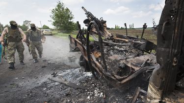 americateve | Dos rebeldes armados pro rusos caminan hacia un cami&oacute;n militar que fue incendiado durante enrentamientos con efectivos del gobierno en la aldea de Oktyabrskoye, a unos 20 kil&oacute;metros (12 millas) de Kramatorsk, en el este de Ucrania, el mi&eac