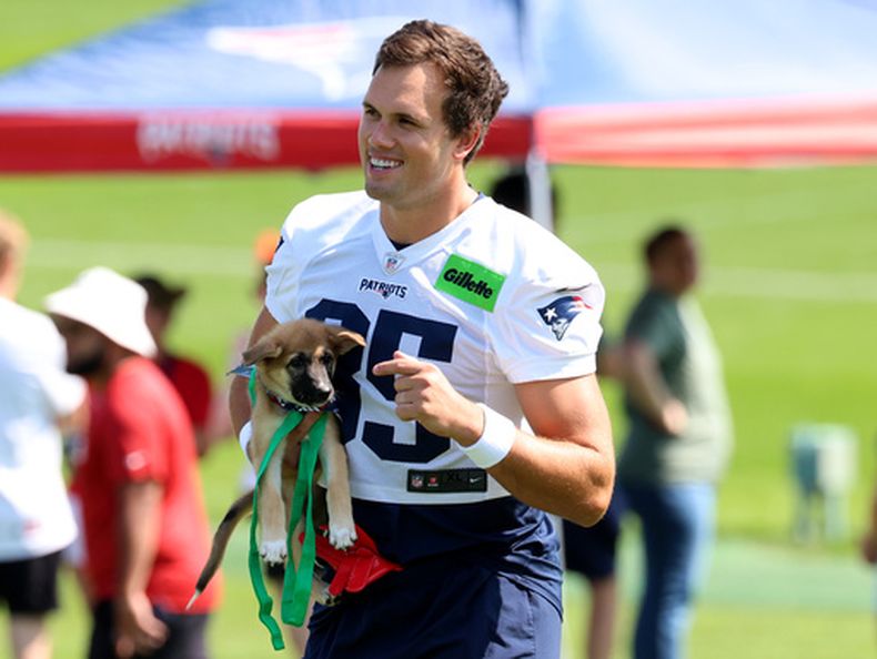 El ala cerrada de los Patriots de Nueva Inglaterra, Hunter Henry, camina con un perro, parte del programa de adopción de perros del equipo en el primer día del campamento de entrenamiento de fútbol americano, el sábado 25 de julio de 2026, en Foxborough, Massachusetts. (Foto AP/Mark Stockwell)