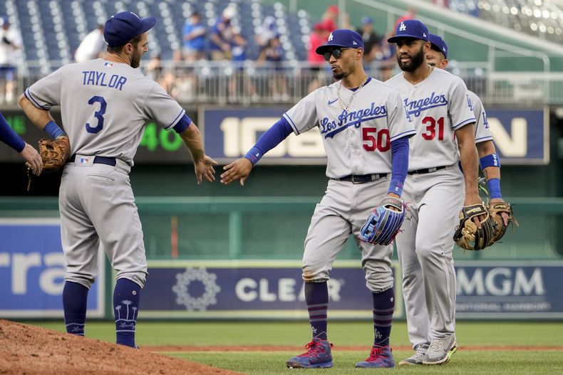 El campocorto de los Dodgers de Los Ángeles Chris Taylor (3) junto al jardinero derecho Mookie Betts (50) y el campocorto dominicano Amed Rosario (31) celebran el triunfo sobre los Nacionales de Washington, en el Nationals Park, en Washington. Domingo 10 de septiembre de 2023. (AP Foto/Andrew Harnik)