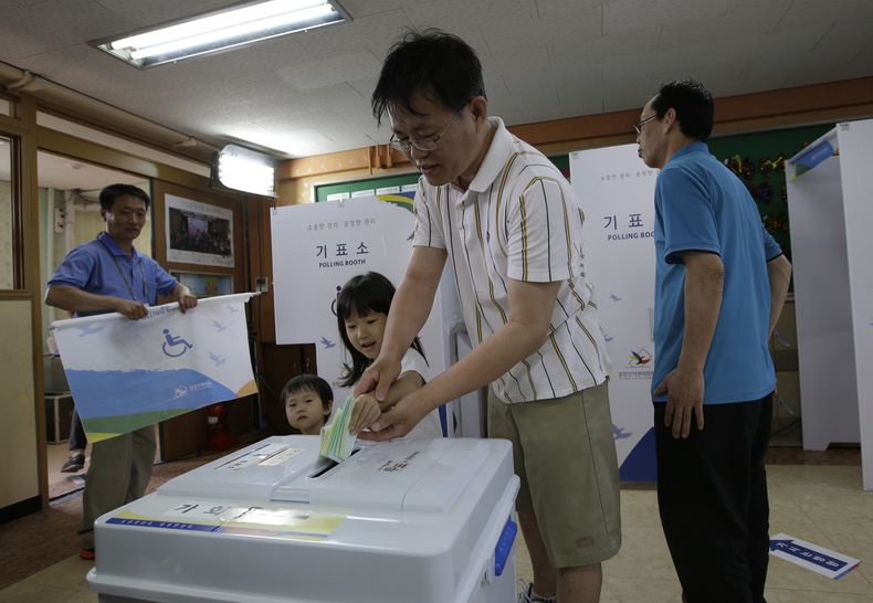 Un hombre coloca su voto en la urna junto con sus hijos en Se&uacute;l, en las elecciones locales que se celebran en Corea del Sur el mi&eacute;rcoles 4 de mayo de 2014. (Foto de AP/Lee Jin-man)