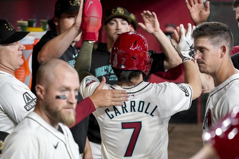 Corbin Carroll (7), de los Diamondbacks de Arizona, choca los cinco con sus compañeros de equipo después de anotar su primera carrera contra los Tigres de Detroit durante la primera entrada de un juego de béisbol, el domingo 19 de mayo de 2024, en Phoenix. Carroll estaba a salvo. (AP Foto/Darryl Webb)