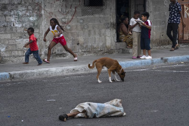 Las piernas de un hombre descuartizado sobresalen de una bolsa tirada en una calle donde hay niños jugando y perros, en el vecindario de Colinas de La Florida, en Guayaquil, Ecuador, el 1 de octubre de 2023. Las piernas estuvieron tiradas en la calle durante horas hasta que fueron recogidas por las autoridades. El resto del cuerpo se encontró esparcido a unas cuadras de distancia. (AP Foto/Rodrigo Abd)