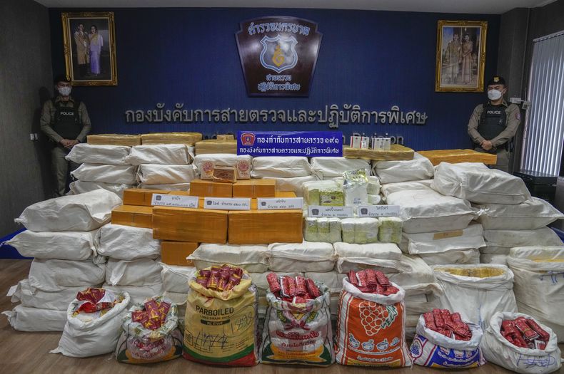 ARCHIVO - Agentes de policía tailandeses de pie detrás de los paquetes que contienen metanfetamina y heroína incautados durante una conferencia de prensa Bangkok, Tailandia, el 28 de septiembre de 2023. (AP Foto/Sakchai Lalit)