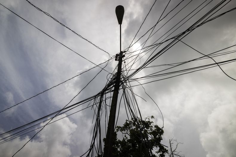 ARCHIVO - Un poste con cableado eléctrico se alza frente a una casa el 15 de septiembre de 2022, en Loiza, Puerto Rico. (AP Foto/Alejandro Granadillo, archivo)