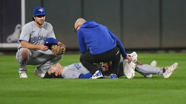 Brett Bateman, centro, jardinero central de los Azulejos de Toronto, yace tendido en el campo y es revisado por un asistente del equipo después de sufrir una lesión durante la segunda entrada del juego de béisbol de Grandes Ligas contra los Orioles de Baltimore, el lunes 21 de septiembre de 2026, en Baltimore. (AP Foto/Stephanie Scarbrough)