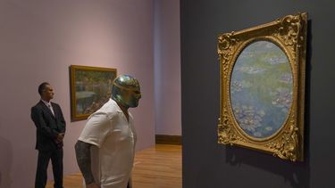 El luchador mexicano CintaDeOro observa una pintura de Claude Monet durante la inauguración de la exposición “Monet. Luces del Impresionismo” en la Ciudad de México el 26 de abril de 2023. (Foto AP/Fernando Llano)