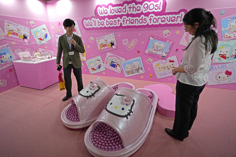 Visitantes reaccionan ante unas zapatillas gigantes de Hello Kitty en la exposición A medida que yo cambio, ella también, que marca el 50 aniversario de Hello Kitty en el Museo Nacional de Tokio el miércoles 30 de octubre de 2024. (Foto AP/Shuji Kajiyama)