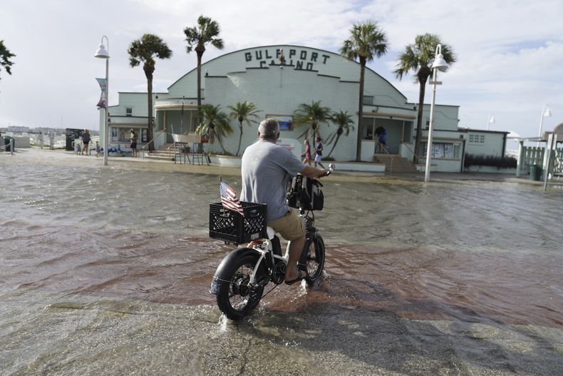 Louis Ward, 57, avanza en su bici por una avenida inundada mientras el huracán Helene se desplaza hacia el noroeste de Florida, el jueves 26 de septiembre de 2024, en Gulfport. (Martha Asencio-Rhine/Tampa Bay Times vía AP)