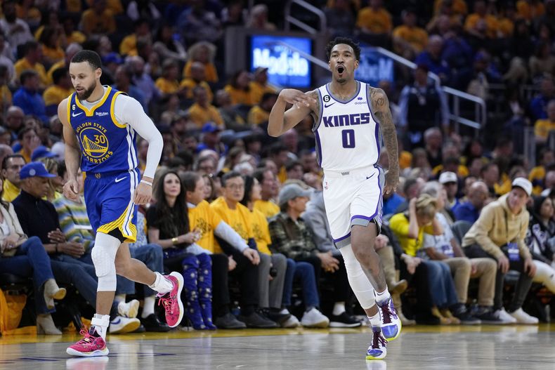 Malik Monk, base de los Kings de Sacramento, festeja luego de atinar un triple junto a Stephen Curry, base de los Warriors de Golden State, en el encuentro de playoffs disputado el viernes 28 de abril de 2023 (AP Foto/Godofredo A. Vásquez)