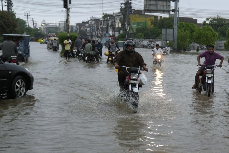 Motoristas circulan por una calle inundada a causa de las intensas lluvias del monzón, en Lahore, Pakistán, el 5 de julio de 2023. (AP Foto/K.M. Chaudary)