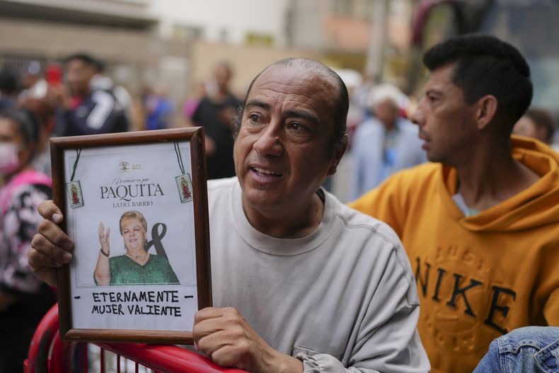 Un hombre muestra una imagen enmarcada de la leyenda mexicana de la música Paquita la del Barrio mientras admiradores esperan la llegada de la carroza fúnebre con sus restos para un homenaje, en Ciudad de México, el viernes 21 de febrero de 2025. (Foto AP/Eduardo Verdugo)