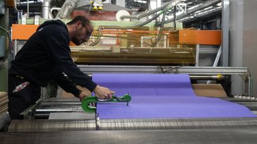 Un trabajador revisa la superficie final para la pista de atletismo para los Juegos Olímpicos de París en la fábrica de Mondo en Alba, al norte de Italia el miércoles 13 de marzo del 2024. (AP Foto/Luca Bruno)