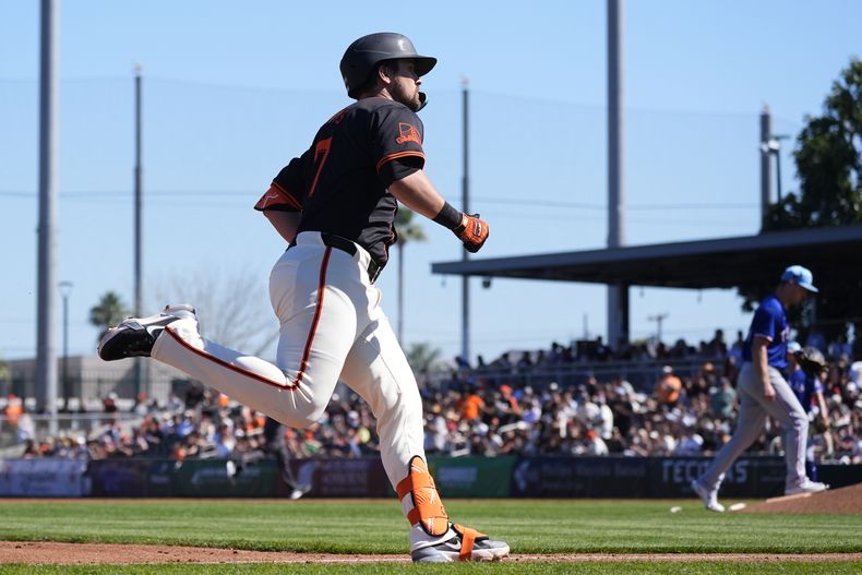 J.D. Davis, de los Gigantes de San Francisco, rodean las bases después de batear un jonrón de tres carreras en contra del abridor de los Rangers de Texas, Adrian Sampson, al fondo, durante la segunda entrada del juego de béisbol del viernes 1 de marzo de 2024, en Scottsdale, Arizona. (AP Foto/Ross D. Franklin)