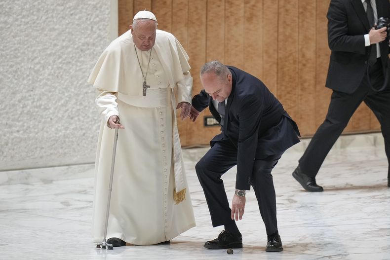 Un ayudante del papa Francisco se agacha para recoger una pieza del bastón del pontífice, a su llegada a una audiencia por el jubileo en el salón Pablo VI del Vaticano, el 1 de febrero de 2025. (AP Foto/Andrew Medichini)