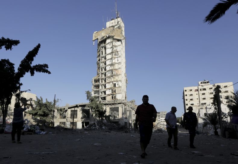Palestinos caminan frente al derruido edificio conocido como el Complejo Italiano en Ciudad de Gaza el 26 de agosto del 2014. El primer ministro israel&iacute; Benjamin Netanyahu declar&oacute; el mi&eacute;rcoles 27 de agosto que Israel gan&oacute; la gu