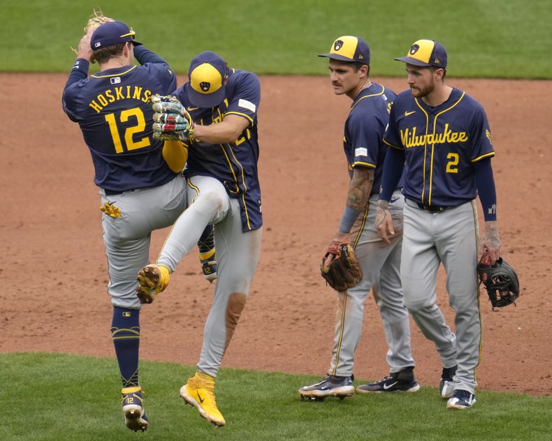 Rhys Hoskins (12), de los Cerveceros de Milwaukee, celebra con Willy Adames mientras Joey Ortiz, segundo desde la derecha, y Brice Turang (2) observan al final de un juego contra los Piratas de Pittsburgh en Pittsburgh, el jueves 26 de septiembre de 2024. Los Cerveceros ganaron 5-2. (AP Foto/Gene J. Puskar)