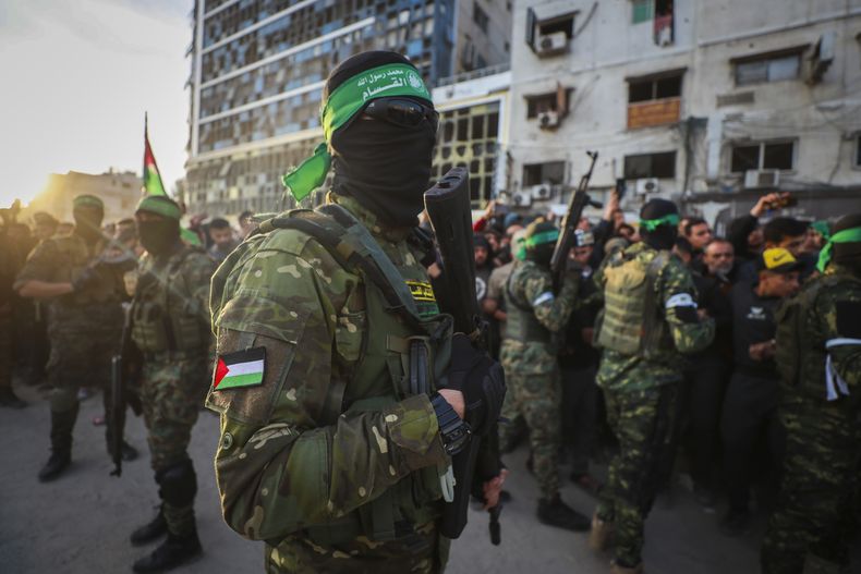 ARCHIVO - Combatientes de las Brigadas Qassam, el ala militar de Hamás, controlan a la multitud a la llegada de los vehículos de la Cruz Roja para recoger a rehenes israelíes durante un acuerdo de cese de fuego entre Israel y Hamas, en Ciudad de Gaza, el 19 de enero de 2025. (AP Foto/Abed Hajjar, archivo)