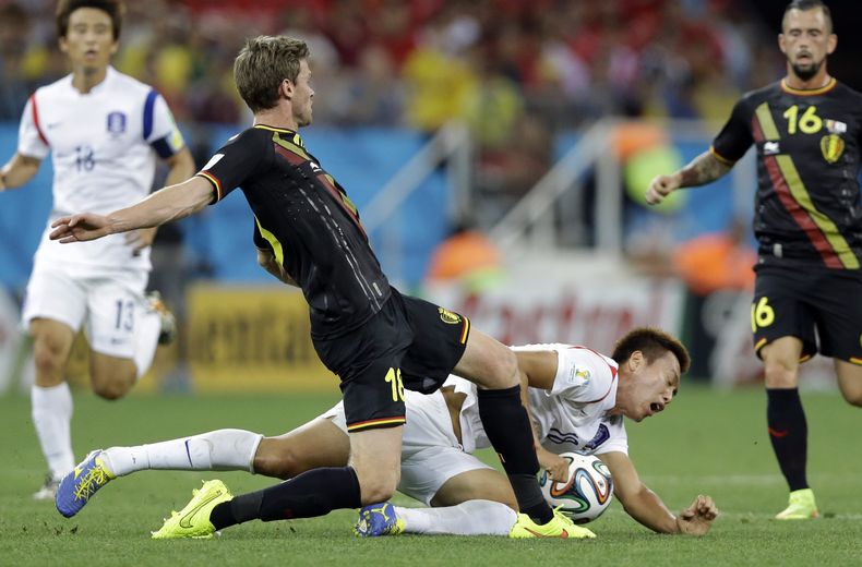 Nicolas Lombaerts, de B&eacute;lgica, patea el bal&oacute;n mientras el surcoreano Kim Shin-wook cae durante el encuentro de la Copa del Mundo realizado el jueves 26 de junio de 2014, en Sao Paulo (AP Foto/Kirsty Wigglesworth)