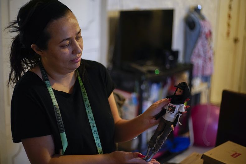 ARCHIVO - Delia Quiroa sostiene una de sus muñecas Barbie disfrazadas de Madre Buscadora, con una foto de su hermano desaparecido, Roberto, y el texto Buscándote, en la Ciudad de México, el 24 de julio de 2023. Quiroa se postula para jueza de distrito en el estado mexicano de Sinaloa en las próximas elecciones judiciales del 1 de junio. (Foto AP/Eduardo Verdugo, Archivo)