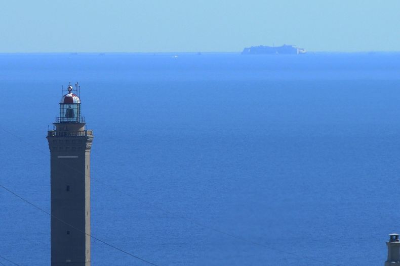 El naufragado curcero Costa Concordia se atriba en el horizonte junto al faro de Lanterna, en G&eacute;nova, el 26 de julio de 2014. El naufragado crucero Costa Concordia ha completado su &uacute;ltimo viaje, y ser&aacute; desmantelado en G&eacute;nova. (