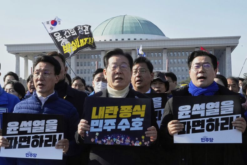 ARCHIVO - El líder del principal partido de la oposición en Corea del Sur, el Partido Democrático, Lee Jae-myung (centro), y otros miembros de la formación corean consignas durante una manifestación a favor de la destitución del presidente, Yoon Suk Yeol, en la Asamblea Nacional, en Seúl, Corea del Sur, el 19 de marzo de 2025. Los carteles dicen Destituyan a Yoon Suk Yeol. (AP Foto/Ahn Young-joon, archivo)