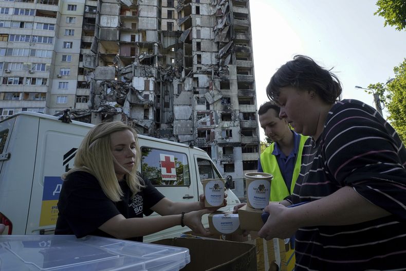 Habitantes locales reciben comida gratuita de voluntarios frente a un edificio de apartamentos dañado por misiles rusos en Járkiv, Ucrania, el viernes 2 de junio de 2023. (AP Foto/Andrii Marienko)