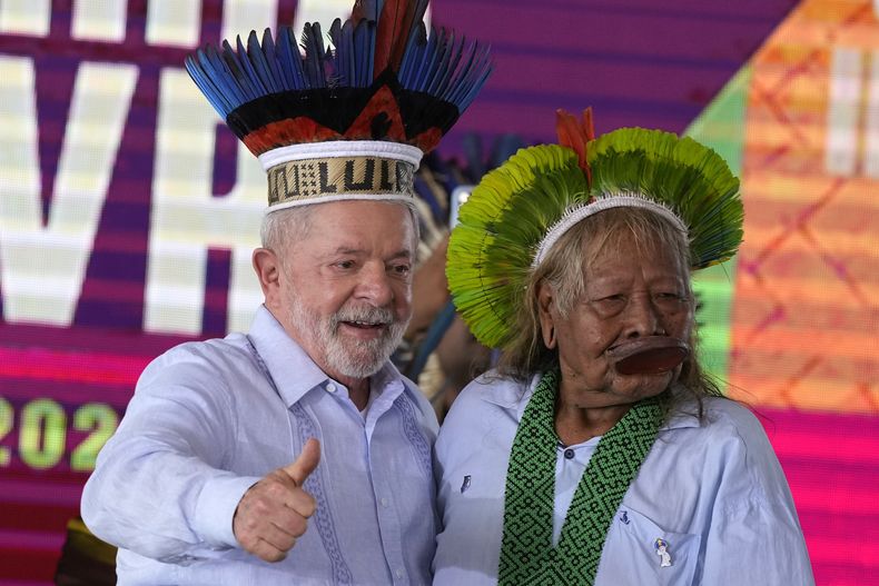 El presidente brasileño Luiz Inácio Lula da Silva hace una señal de aprobación tras recibir un tocado tradicional indígena del jefe Raoni Metuktire, de la etnia caiapo, durante la clausura de un evento el viernes 28 de abril de 2023, en Brasilia. (AP Foto/Eraldo Peres)