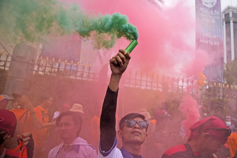 UN trabajador sostiene una bengala durante una manifestación del Primero de Mayo en Yakarta, Indonesia, el lunes 1 de mayo de 2023. Trabajadores y activistas en Asia reclamaban salarios más altos y mejores condiciones de trabajo, entre otras demandas. (AP Foto/Dita Alangkara)