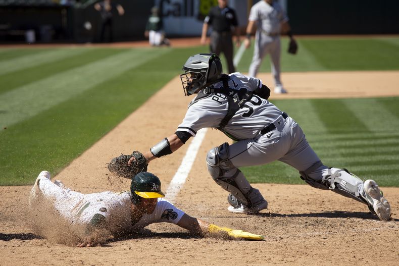 Tyler Wade de los Atléticos de Oakland se desliza en el plato para la carrera de la victoria frente al cátcher de los Medias Blancas de Chicago Carlos Pérez en la décima entrada el sábado 1 de julio del 2023. (AP Foto/D. Ross Cameron)