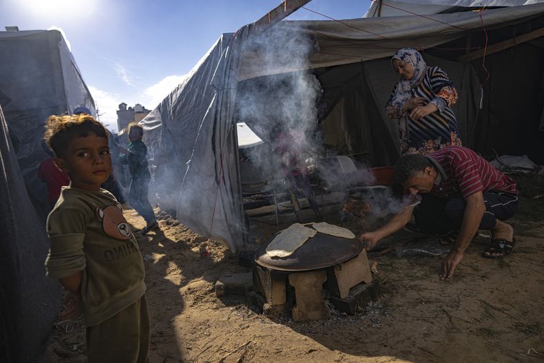 Palestinos desplazados por los bombardeos israelíes en la Franja de Gaza preparan pan en un campamento montado por el Programa de la ONU para el Desarrollo, el miércoles 15 de noviembre de 2023, en Jan Yunis, Franja de Gaza. (AP Foto/Fatima Shbair)