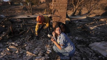 Ella Venne, al frente, sostiene una taza que encontró entre los restos de la casa de su familia , destruida por el incendio Eaton, en Glendale, mientras busca con el capitán de bomberos Chris Jernegan, a la izquierda, y su esposa, Alison, en Altadena, California, el sábado 11 de enero de 2025. (AP Photo/Mark J. Terrill)