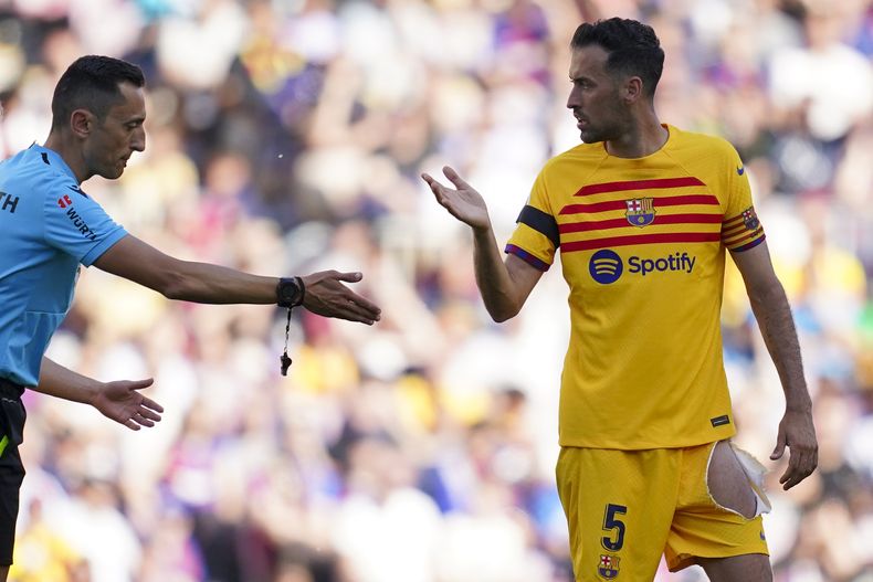 El árbitro José María Sánchez Martínez charla con el volante del Barcelona Sergio Busquets durante el partido contra el Atlético de Madrid por la Liga española, el domingo 23 de abril de 2023. (AP Foto/Joan Mateu) l