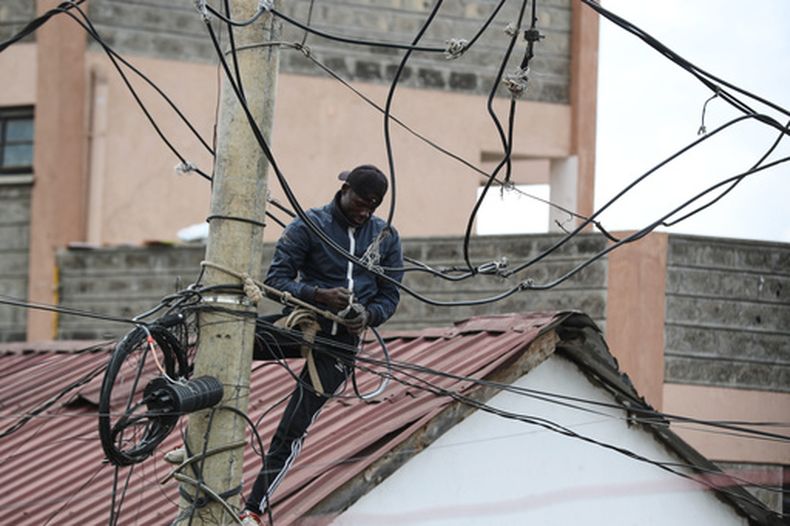 Un hombre conecta cables eléctricos en un poste en el asentamiento informal de Kibera, en Nairobi, Kenia, el 31 de marzo de 2026. (AP Foto/Henry Naminde)