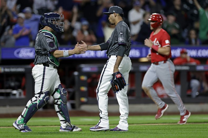 El lanzador de los Mets de Nueva York, Edwin Díaz, y el receptor Francisco Álvarez celebran mientras Tyler Stephenson, de los Rojos de Cincinnati, corre en el fondo después de que los Mets ganaron 4-0 el sábado 7 de septiembre de 2024 en Nueva York. AP Foto/Adam Hunger)