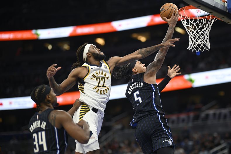 Paolo Banchero (5), del Magic de Orlando, ataca el aro frente a Isaiah Jackson (22), de los Pacers de Indiana, mientras observa Wendell Carter Jr. (34) durante la segunda mitad del juego de baloncesto de la NBA, el lunes 28 de octubre de 2024, en Orlando, Florida. (AP Foto/Phelan M. Ebenhack)