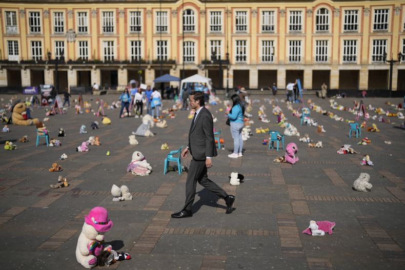 Gente camina entre juguetes que se exhiben en la Plaza Bolívar en un acto simbólico que por séptimo año consecutivo busca llamar la atención de la ciudadanía y del Estado sobre el abuso sexual infantil, en Bogotá, Colombia, el jueves 23 de noviembre de 2023. (AP Foto/Fernando Vergara)