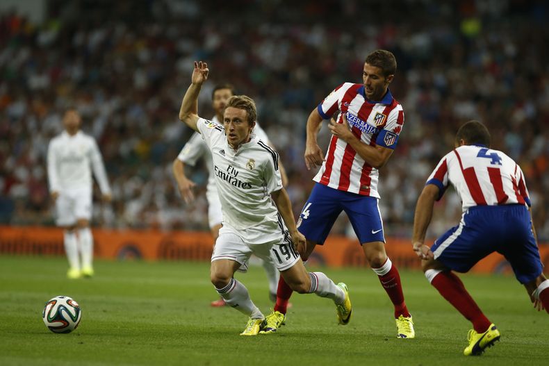 El jugador de Real Madrid, Luka Modric, centro, disputa un bal&oacute;n en un partido contra el Atl&eacute;tico de Madrid el martes, 19 de agosto  de 2014, en Madrid. (AP Photo/Andres Kudacki)