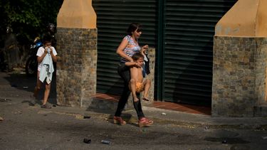 americateve | Una mujer busca refugiarse con su hijo del gas lacrim&oacute;geno que lanzaron soldados contra manifestantes durante una protesta antigubernamental en Caracas, Venezuela, el s&aacute;bado 26 de abril de 2014. Las autoridades anunciaron la captura de un in