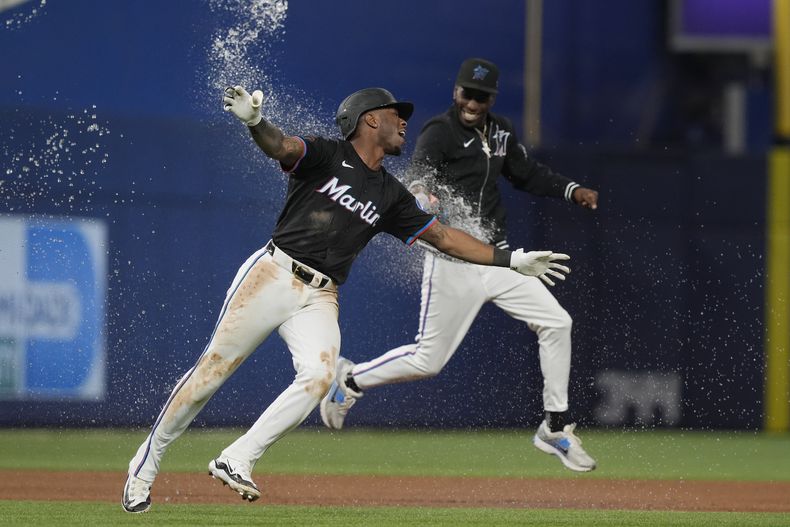 Tim Anderson (izquierda), de los Marlins de Miami, corre para festejar tras pegar el hit decisivo del duelo ante los Marineros de Seattle, el viernes 21 de junio de 2024 (AP Foto/Marta Lavandier)