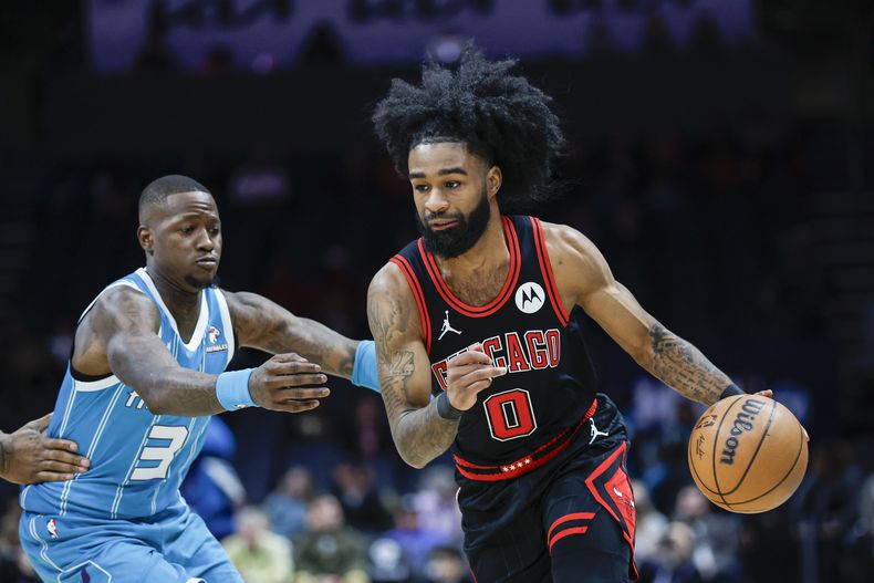 El base de los Bulls de Chicago Coby White avanza hacia la canasta con el balón frente al base de los Hornets de Charlotte Terry Rozier en el encuentro del lunes 8 de enero del 2024. (AP Foto/Nell Redmond)