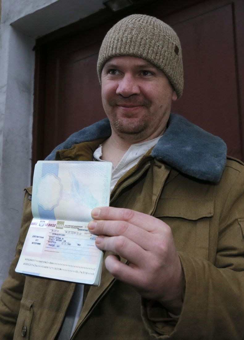 El brit&aacute;nico Anthony Perrett, activista de Greenpeace, muestra a la prensa su pasaporte con la visa que le permite salir de Rusia cerca del Servicio Federal de Migraci&oacute;n en San Petersburgo, el jueves 26 de diciembre de 2013. La fiscal&iacute