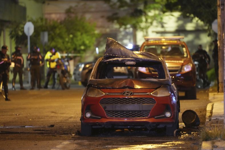 Un vehículo que explotó frente al edificio del Ministerio de la Mujer y Derechos Humanos es acordonado por las autoridades en Quito, Ecuador, la noche del miércoles 30 de agosto de 2023. El edificio solía ser la ubicación del Servicio Nacional de Atención a Personas Privadas de Libertad que gestiona el sistema penitenciario. (AP Foto/Dolores Ochoa)