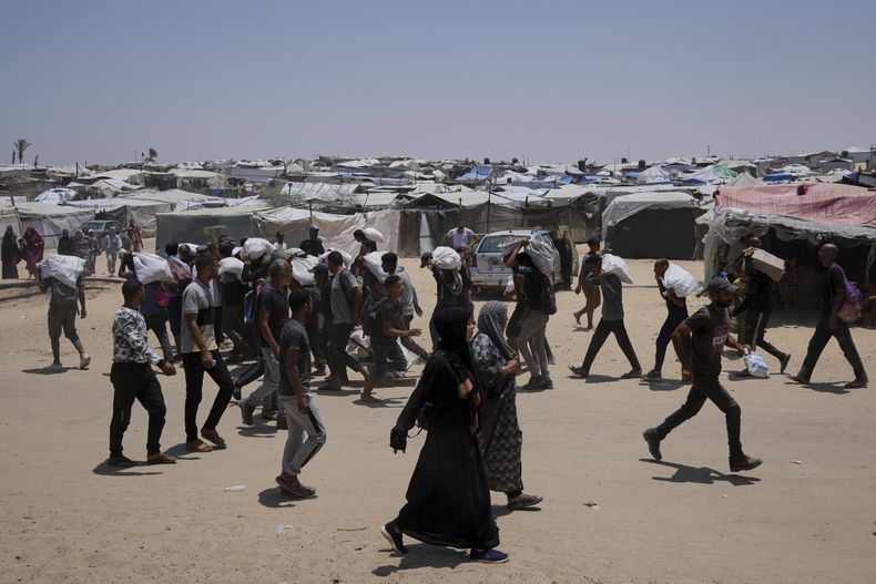 Palestinos llevan bolsas con comida y ayuda humanitaria en Rafah, Franja de Gaza, el 8 de junio del 2025. (AP foto/Abdel Kareem Hana)