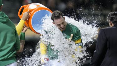 Brent Rooker, de los Atléticos de Oakland, recibe una ducha de agua helada tras sacudir un jonrón de tres carreras que dio la victoria a su equipo frente a los Rangers de Texas en el 10mo inning del juego de la MLB que los enfrentó en Oakland, California, el 12 de mayo de 2023. (AP Foto/Godofredo A. Vásquez)