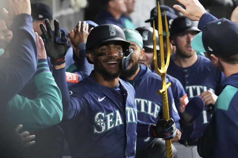El dominicano Julio Rodríguez de los Marineros de Seattle celebra con sus compañeros en el dugout su grand slam en la octava entrada ante los Medias Blancas de Chicago el lunes 19 de mayo del 2025. (AP Foto/Nam Y. Huh)